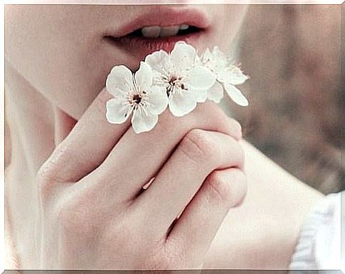 Girl holding a few white flowers as an example of how beautiful minimalism can be and why becoming minimalist can be beautiful