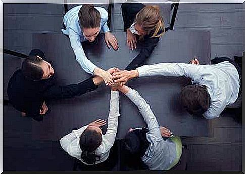 People stand in a circle with their hands on top of each other