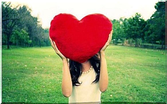 Girl who hides her face behind a big heart because healthy couples feel love for each other