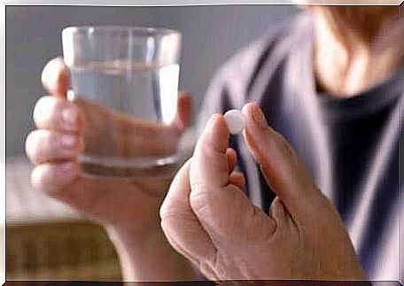 A man takes a pill with a glass of water