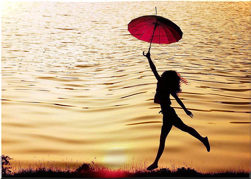 Woman walking along the water with an umbrella and being guided by her intrinsic motivation