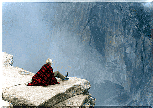 Woman sitting on the edge of an abyss trying to get over her phobia