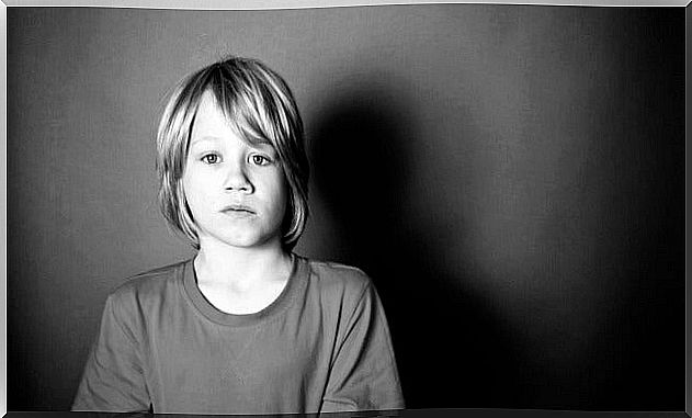 Little boy standing in front of a black background and looking sadly ahead as an example of those forgotten children