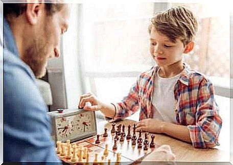 A boy plays chess with his father