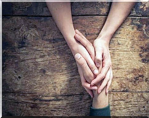 A woman holds a man's hand over a table